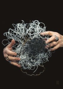 two hands holding a nest of black and white wires taken from ring binders of books