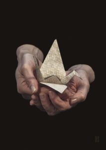 two hands gently holding an origami paper crane