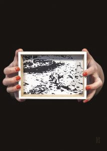 two hands holding small black and white framed image
