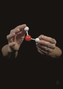 two hands. holding a plastic molecular model of water
