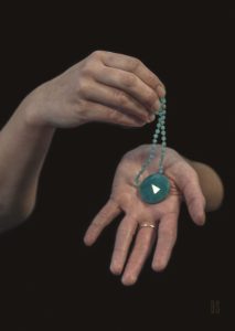 one hand holding green glass necklace which is resting on outstretched hand
