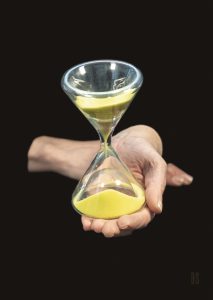 one hand holding an hourglass with yellow sand running down
