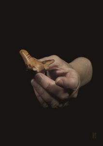 one hand holding a small terracotta bird with a broken wing